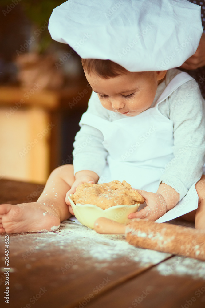 The small baby sitting on the table and playing with dough The small baby sitting on the table and playing with dough