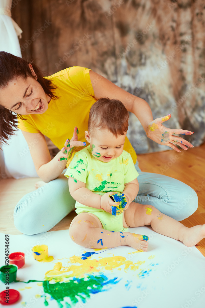 The mother with son painting a big paper by hands The mother with son painting a big paper by hands