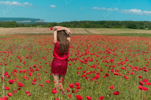Fototapeta Naklejka Na Ścianę i Meble -  A girl in red dress in huge poppy field 