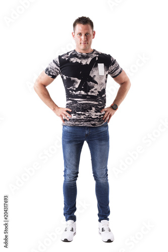 Satisfied smiling young adult man with hands on hips looking at camera in casual clothes. Full body isolated on white background. 