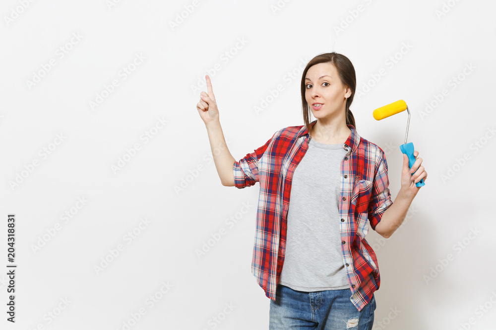 Young concerned woman holding paint roller for wall painting and pointing index finger up on copy space isolated on white background. Instruments for renovation apartment room. Repair home concept. Young concerned woman holding paint roller for wall painting and pointing index finger up on copy space isolated on white background. Instruments for renovation apartment room. Repair home concept.