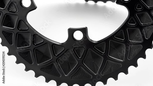 Black oval bicycle chainring gear rotating at white background, strong close up with visible details of structure photo