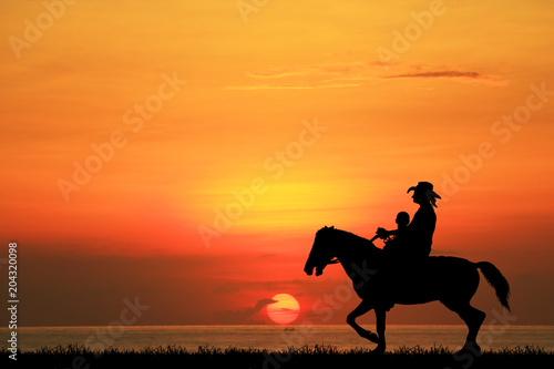 silhouette cowboy and son riding horse on sunrise.