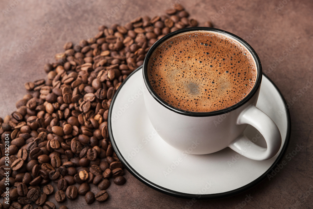 Obraz premium Coffee in a white cup with roasted beans