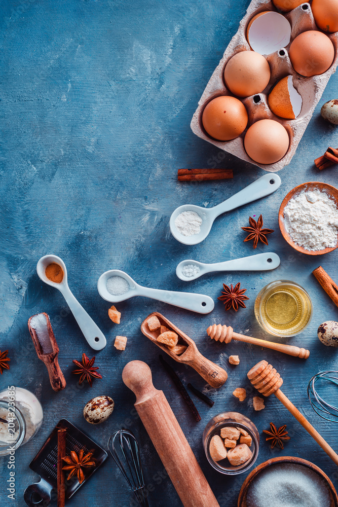 Cooking tools and ingredients from above. Baking concept with measuring  spoons, wooden scoops, whisks, cookie cutters, sugar, flour, eggs and  cinnamon on a modern concrete background with copy space Stock Photo