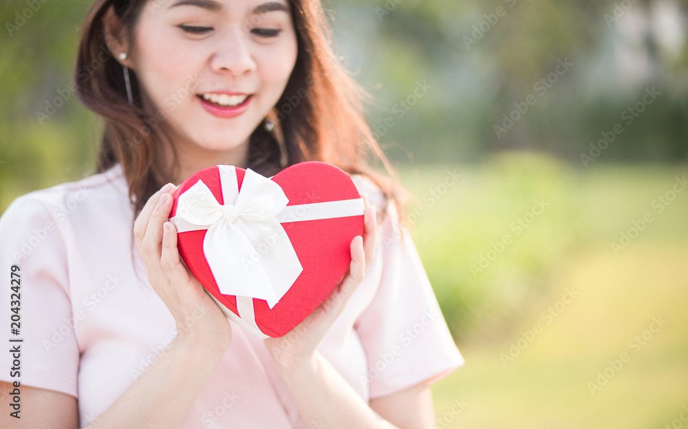 Selective focus Woman hold red gift heart box in the park . Concept of the Valentine's Day. Selective focus Woman hold red gift heart box in the park . Concept of the Valentine's Day.