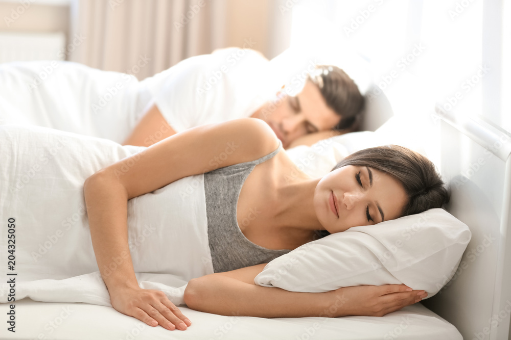 Young couple sleeping on bed with soft pillows at home Young couple sleeping on bed with soft pillows at home