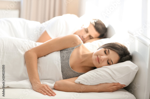 Young couple sleeping on bed with soft pillows at home