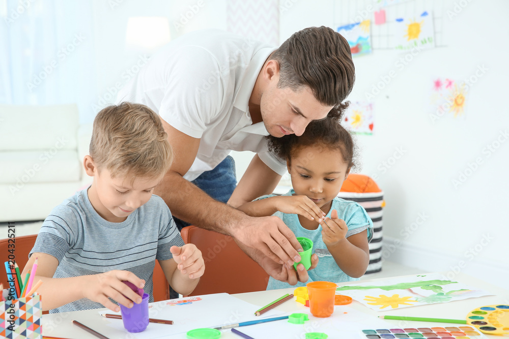 Young man and little kids playing together indoors. Child adoption Young man and little kids playing together indoors. Child adoption