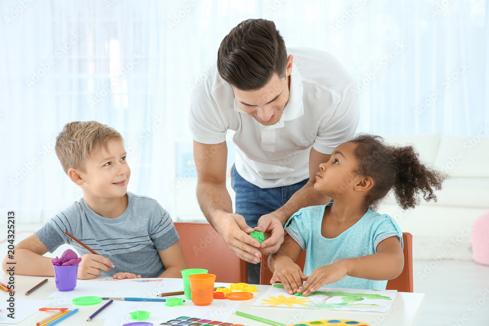 Young man and little kids playing together indoors. Child adoption Young man and little kids playing together indoors. Child adoption