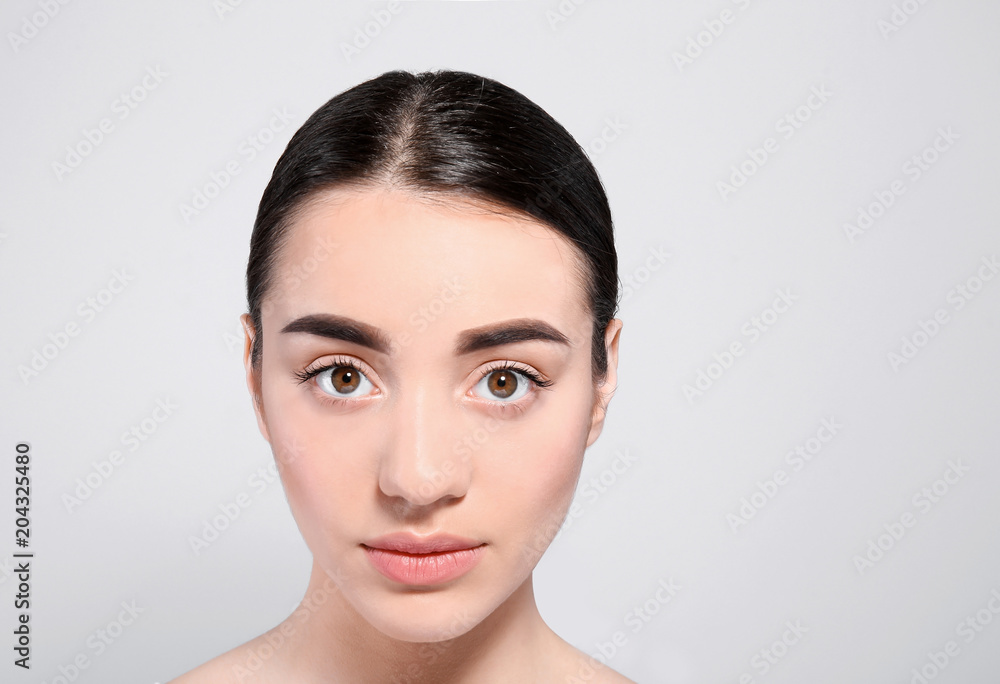 Beautiful woman with perfect eyebrows on light background