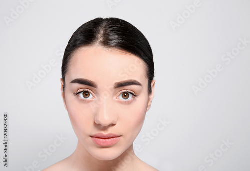 Beautiful woman with perfect eyebrows on light background