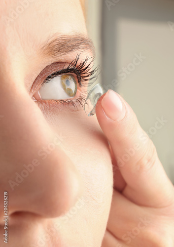 Fototapeta Naklejka Na Ścianę i Meble -  Young woman putting contact lens in her eye, closeup