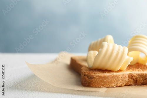 Toasted bread with fresh butter curls on table, closeup
