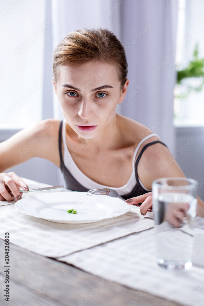 Meal time. Cheerless pale woman sitting at the table while eating her meal Meal time. Cheerless pale woman sitting at the table while eating her meal