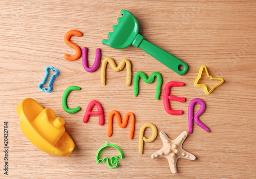Text SUMMER CAMP made with play dough on wooden background, top view