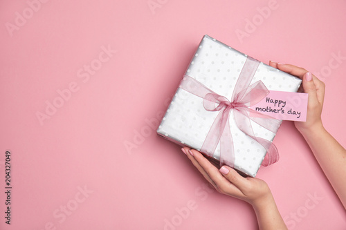 Woman holding elegant gift box for Mother's Day on color background, top view © New Africa