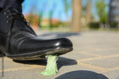 Fotografie Man stepping in chewing gum on sidewalk. Concept of stickiness