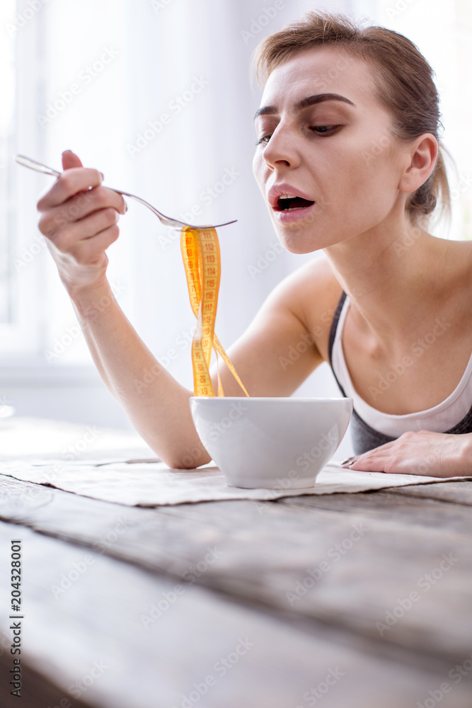 Professional requirements. Unhappy young women looking at her meal while keeping a diet Professional requirements. Unhappy young women looking at her meal while keeping a diet