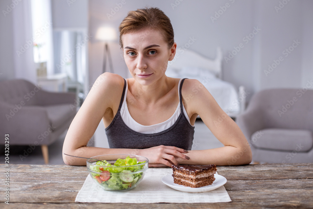 What to choose. Pleasant nice woman sitting at the table while looking at you What to choose. Pleasant nice woman sitting at the table while looking at you