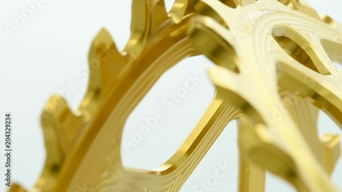 Golden oval bicycle chainring gear rotating at white background, strong close up with visible details of structure photo