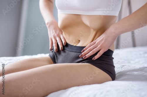 Too slim. Waist of a underweight young woman while sitting on the bed