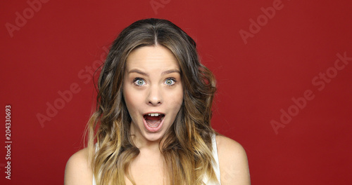 Female Face in Shock, Close Up. Portrait young surprised and shockedwoman on red. Amazed by Surprise, Excited Brunette Woman, White Background