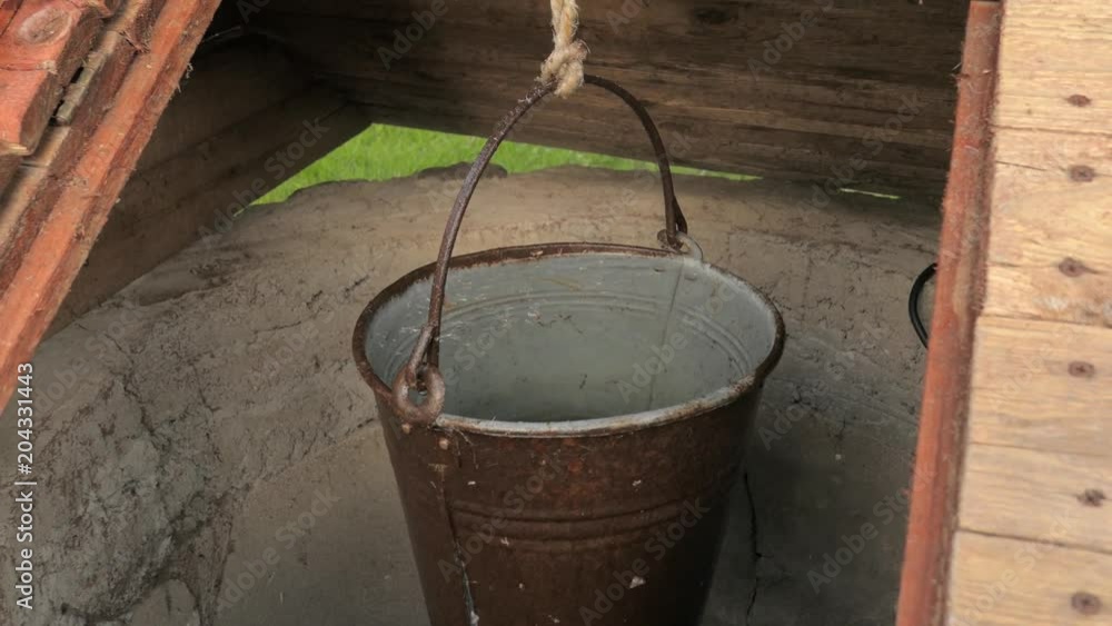 metal bucket full of water hanging in a rural well metal bucket full of water hanging in a rural well