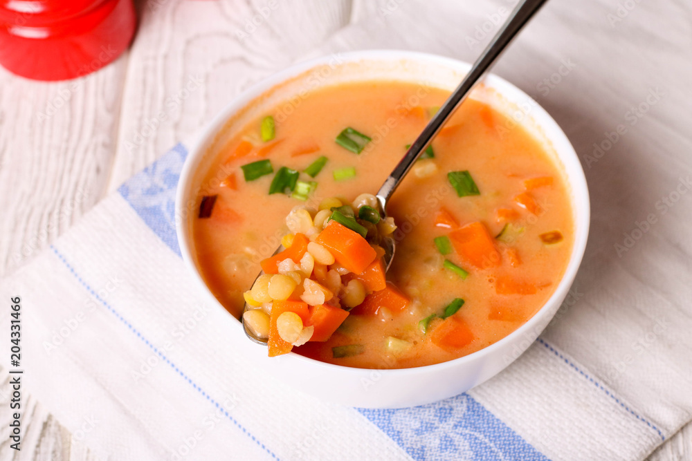 Vegetarian and vegan yellow split pea soup, carrot in white bowl