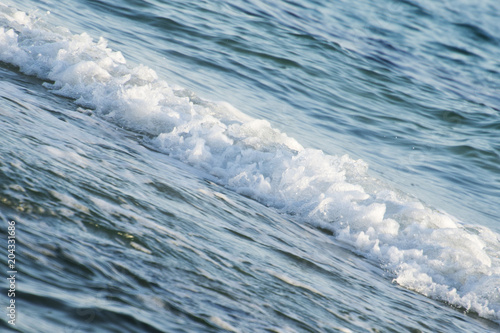 A small wave on a flat water surface. Abstract background photo