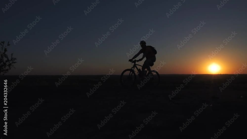 A young man is actively spending time on his bike at sunset. A bike ride in the sunset A young man is actively spending time on his bike at sunset. A bike ride in the sunset