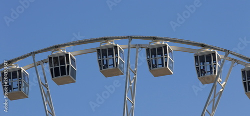 Wheel of view with cabins against the sky. Widescreen photo, fragment