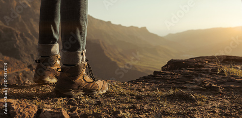 Close up of hikers boots enjoying sunset at the top of the mountains with copy space photo