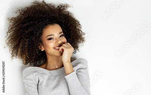 Portrait Of Beautiful Smiling Black Woman With Fresh Face, Soft Skin Having Fun Lying On White Background © kiuikson