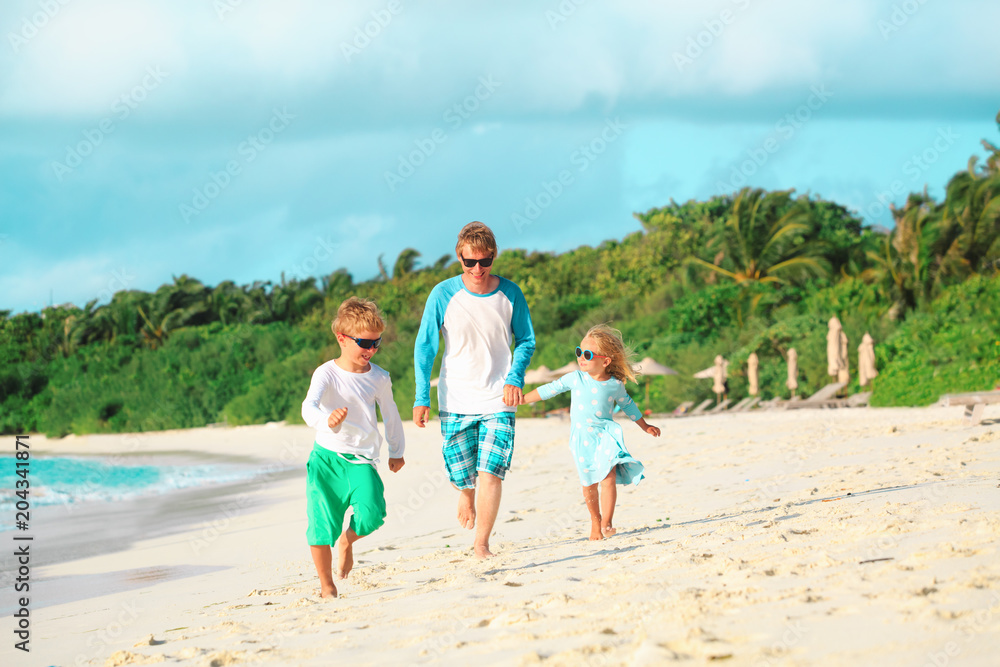 father with little son and daughter run at beach father with little son and daughter run at beach