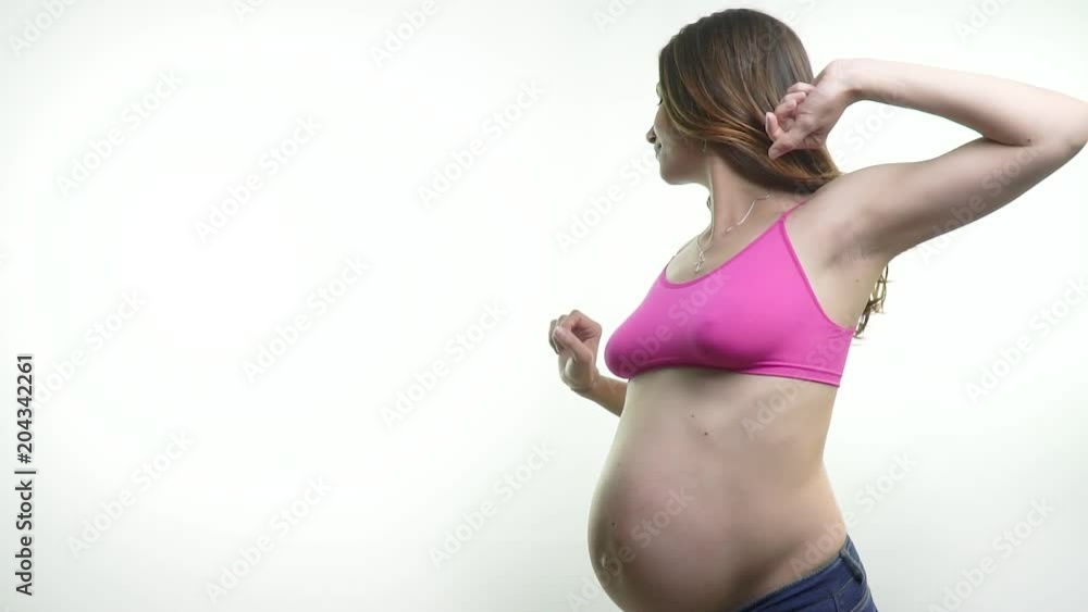 Pregnant brunette woman is training while standing on a white background Pregnant brunette woman is training while standing on a white background