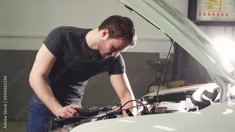 Young Technician Man Making Engine Service of Car in Garage. Young Technician Man Making Engine Service of Car in Garage.