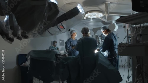 Operating room, team of surgeons prepares patient to cancer removal surgery via Minimally Invasive Robotic Surgery with the Da Vinci Surgical System. Hi-tech medical robot