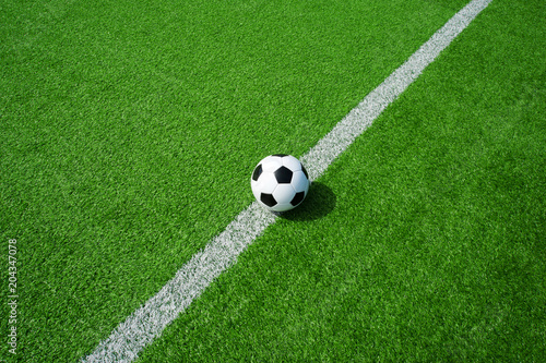 Klassischer Fussball schwarz weiss auf der Linie mit grünem Kunstrasen in der Sonne im Sommer