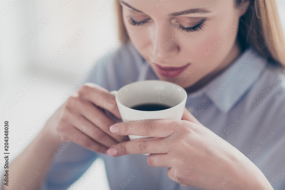 Close up cropped portrait of charming, pretty, nice, cute woman holding mug of aromatic coffee near her mouth, enjoying aroma with close eyes