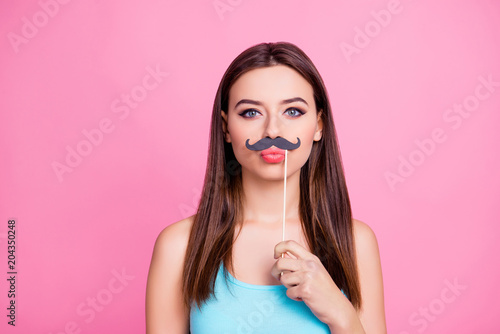 Portrait of cheerful cute lovely comic beautiful humorous sexy stunning amusing lovable appealing girl applying fake mustache on face sending air kiss, isolated on vivid pink background