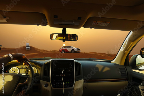 Fototapeta Naklejka Na Ścianę i Meble -  Off road safari with SUV vehicles in the desert at sunset, view from the car
