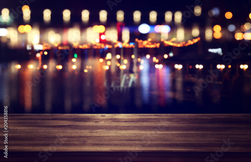 Image of wooden table in front of abstract blurred restaurant lights background. © tomertu