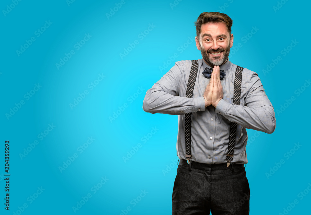 Middle age man, with beard and bow tie with hands together in praying gesture, expressing hope and please concept Middle age man, with beard and bow tie with hands together in praying gesture, expressing hope and please concept