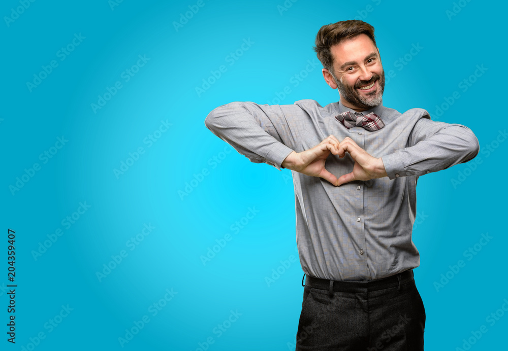 Middle age man, with beard and bow tie happy showing love with hands in heart shape expressing healthy and marriage symbol Middle age man, with beard and bow tie happy showing love with hands in heart shape expressing healthy and marriage symbol