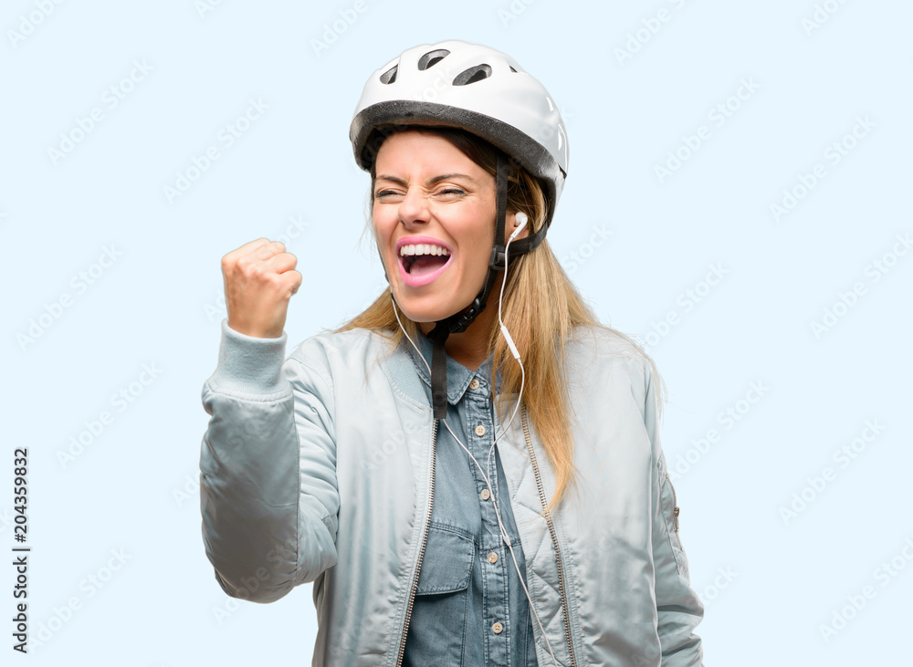 Young woman with bike helmet and earphones irritated and angry expressing negative emotion, annoyed with someone Young woman with bike helmet and earphones irritated and angry expressing negative emotion, annoyed with someone