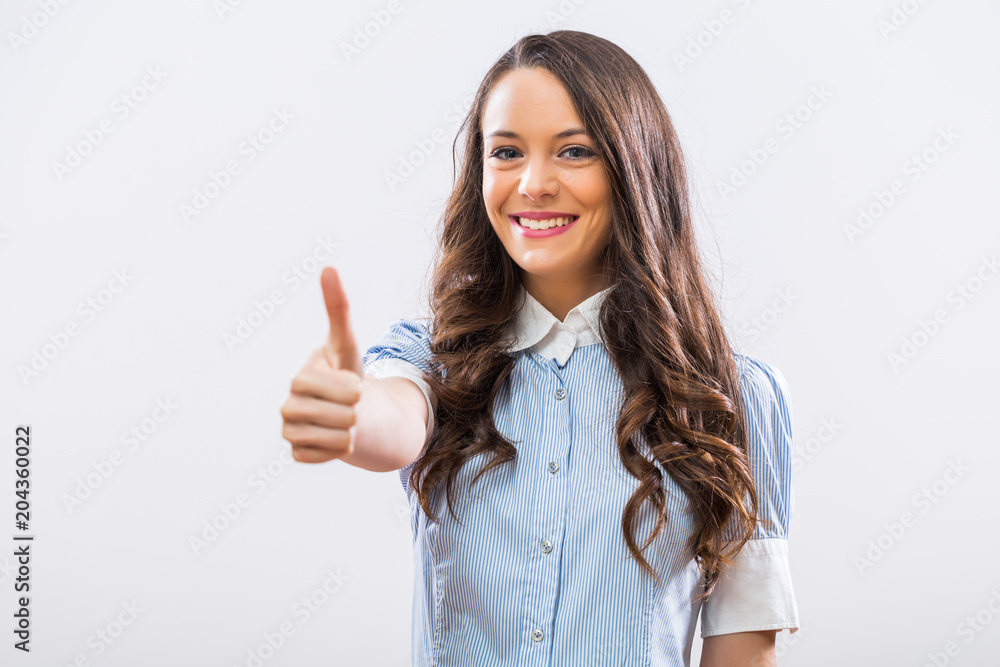 Portrait of beautiful businesswoman showing thumb up on gray background. Portrait of beautiful businesswoman showing thumb up on gray background.