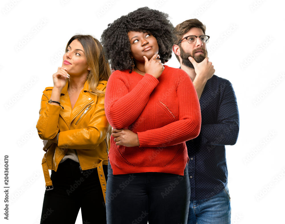 Group of three young men and women thinking and looking up expressing doubt and wonder Group of three young men and women thinking and looking up expressing doubt and wonder