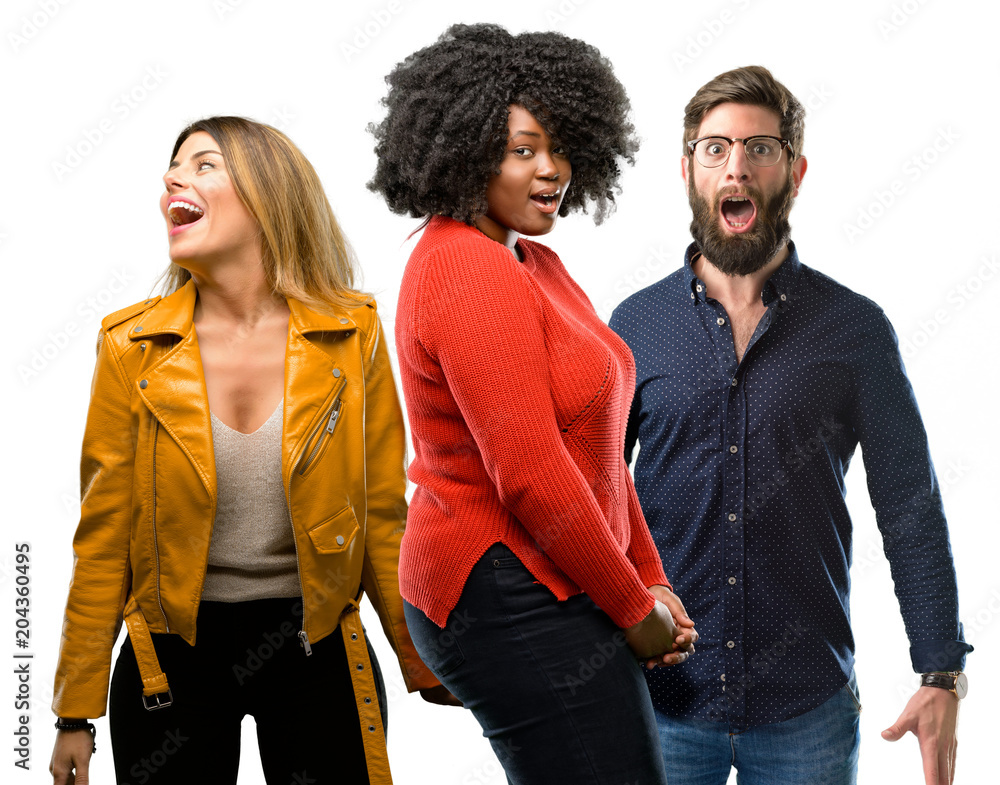Group of three young men and women happy and surprised cheering expressing wow gesture Group of three young men and women happy and surprised cheering expressing wow gesture
