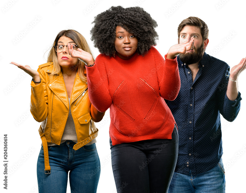 Group of three young men and women doubt expression, confuse and wonder concept, uncertain future shrugging shoulders Group of three young men and women doubt expression, confuse and wonder concept, uncertain future shrugging shoulders